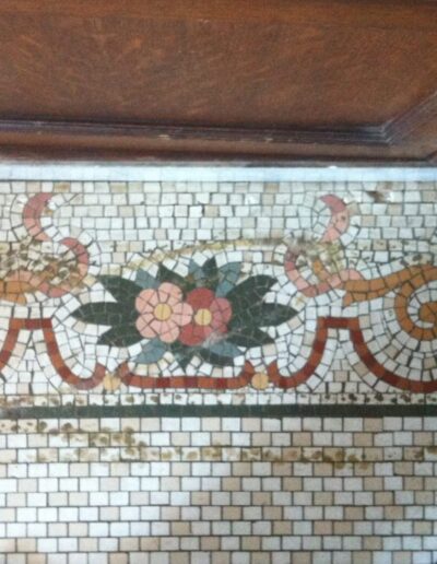 The mosaic tile floor was damaged along the edge and left dirty after years of being covered by carpet.